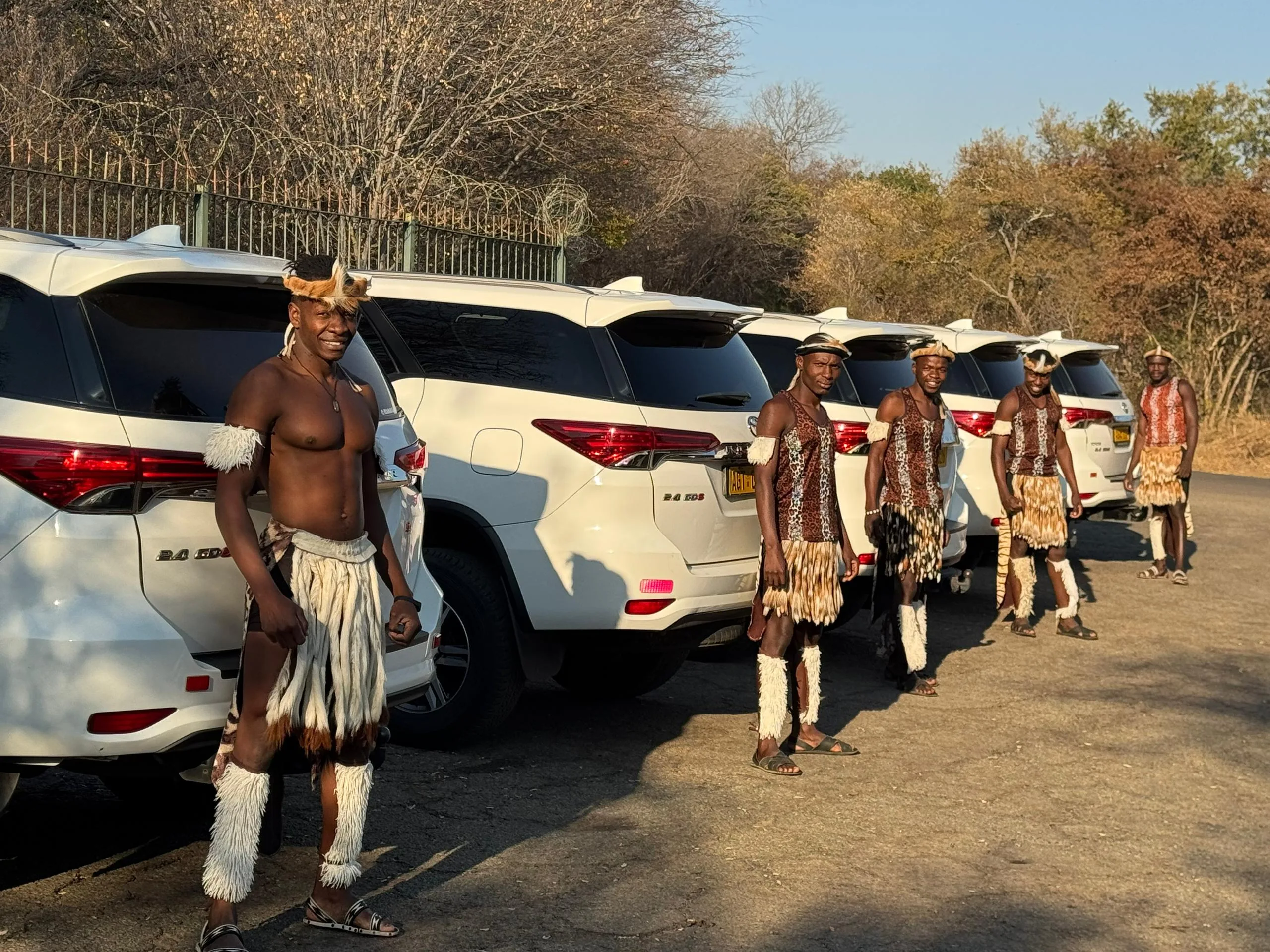Traditional dancers greeting guests with fleet in the background